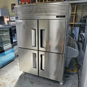 The SANDEN 2 DOOR STAINLESS STEEL FRIDGE, with a reflective finish and wheels, is displayed among other appliances—perfect for anyone needing reliable restaurant or commercial catering equipment. MRCE