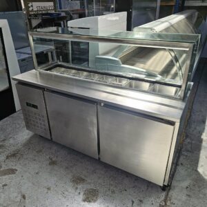 The 1800MM SANDWICH PREPERATION FRIDGE features a stainless steel counter, glass sneeze guard, eight ingredient trays, and two refrigerated compartments—perfect for restaurants, warehouses, or kitchen equipment buyers. MRCE