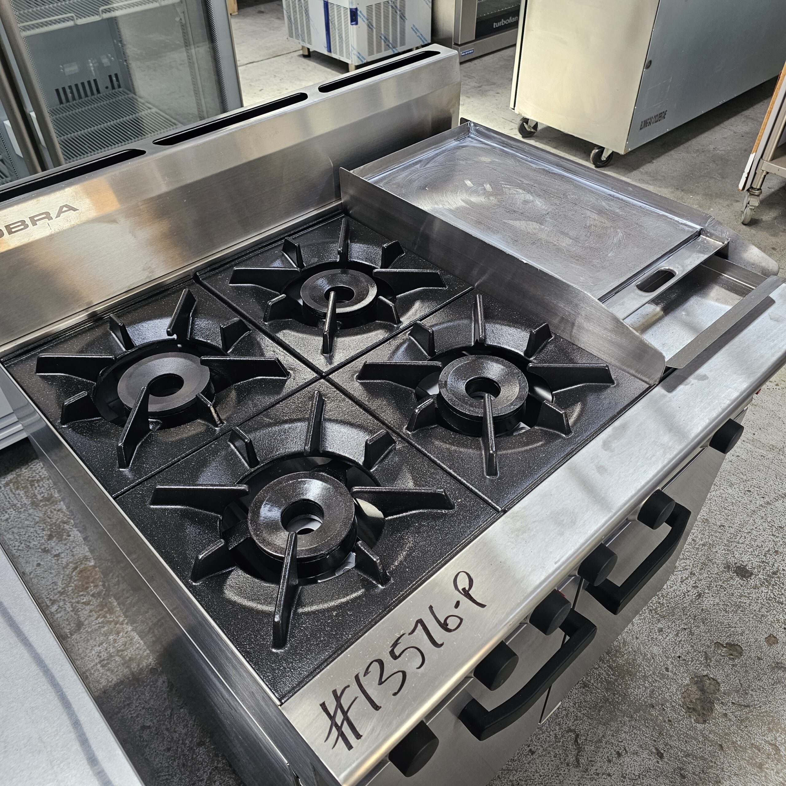 Stainless steel commercial gas stove with four burners and a flat griddle on the right side. The unit is labeled #13576-P and is situated in an industrial kitchen setting. MRCE