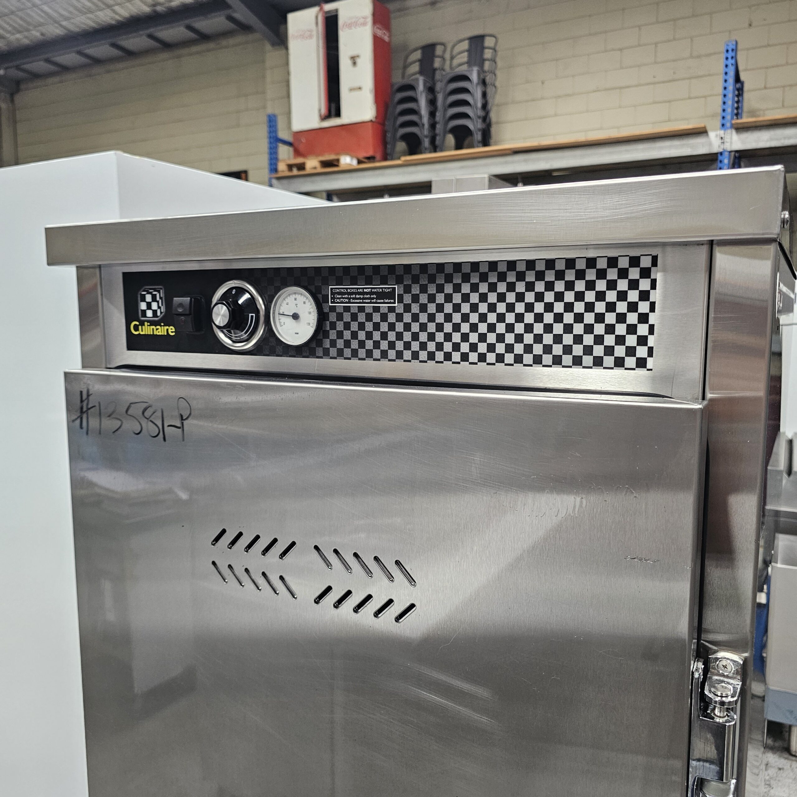 A stainless steel commercial kitchen appliance with a checkered panel, gauge, and control knobs. The label reads Culinaire. #15584P is written on the side in black marker. Shelving and equipment are visible in the background. MRCE